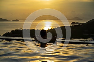 The young man watched the sunset view while swimming from the pool