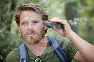 young man watching birds trought binoculars