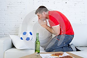 Young man watching football game on television nervous and excited suffering stress praying god for goal