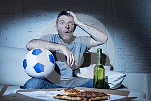 Young man watching football game on tv nervous and excited suffering stress on couch