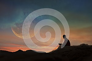 Young man is watching the full moon on a beautiful sunset