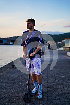 young man watching his electric scooter down the promenade