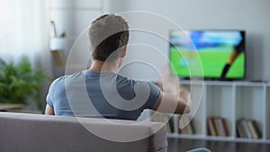 Young man watching soccer match home, criticizing football team for defeat