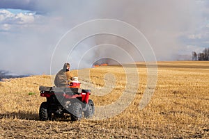 A young man watching a straw field on fire