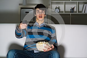 Young man watching television with popcorn