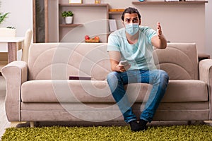 Young man watching tv at home during pandemic