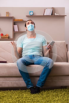 Young man watching tv at home during pandemic