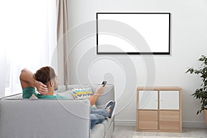 Young man watching TV on sofa at home