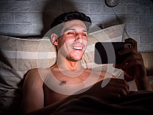 Young man watching a video on cell phone in bed
