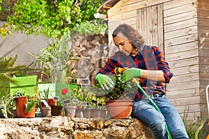 Young man watering potted flowers using hosepipe