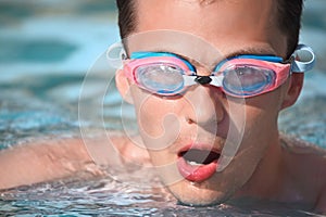 Young man in watersport goggles swimming in pool