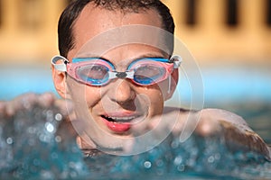 Young man in watersport goggles swimming in pool