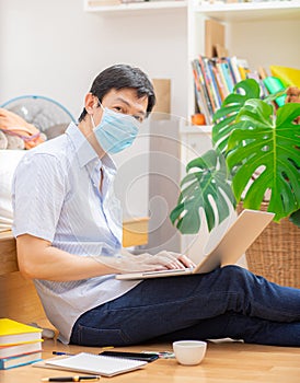 Young man wear mask and studying is working at home with his mobile phone and laptop. Concept of work at home and new technologies