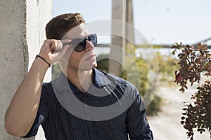 Young man wear sunglasses lean on a colum