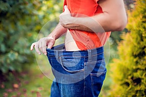 Young man wearing big loose jeans - weight loss concept