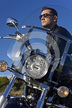 Young man wearing a black leather jacket, sunglasses and jeans s