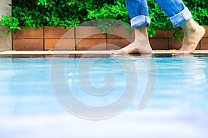 Young man wearing blue Jean walking alone at the edge of the swimming pool.