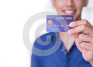 Young man wearing a blue shirt smiling and showing a blue credit card for prepare shopping online. Space for text