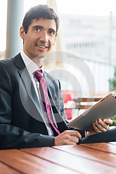Young man wearing business suit while using a tablet PC during b