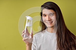 Young man wearing casual shirt holding bottle of water cheerfully smiling, copy space