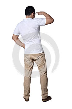 Young man wearing casual white shirt and khaki jeans looking far away gesture, rear view. Full body portrait