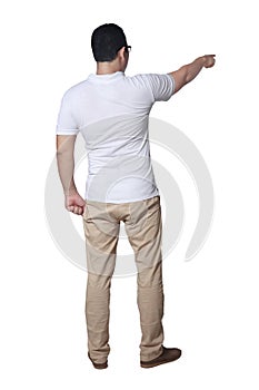 Young man wearing casual white shirt and khaki jeans looking and pointing forward gesture, rear view. Full body portrait