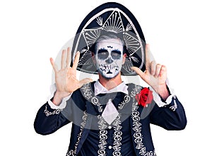 Young man wearing day of the dead costume over background showing and pointing up with fingers number seven while smiling