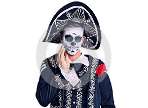 Young man wearing day of the dead costume over background touching mouth with hand with painful expression because of toothache or