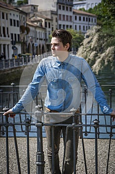 Young man wearing denim shirt on city bridge in Treviso, Italy