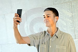 Young man wearing an earbud taking a selfie