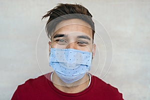 Young man wearing face mask portrait - Latin boy using protective facemask for preventing spread of corona virus