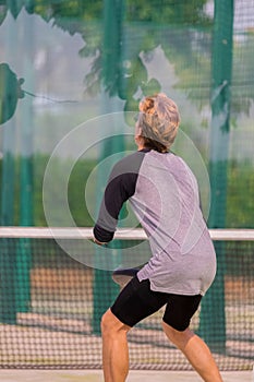 Young man wearing glasses waiting for the ball at a paddle court on an out of focus background. Paddle and lifestyle