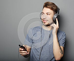 Young man wearing headphones and holding mobile phone