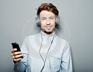 Young man wearing headphones and holding mobile phone