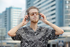 A young man wearing headphones and sunglasses listens to music