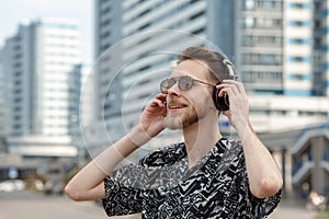 A young man wearing headphones and sunglasses listens to music