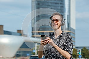 A young man wearing headphones and sunglasses listens to music