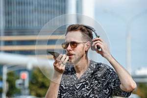A young man wearing headphones and sunglasses listens to music