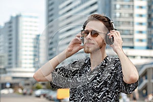 A young man wearing headphones and sunglasses listens to music