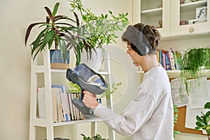 Young man wearing headphones vacuums bookshelves at home