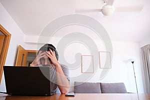 Young man wearing headphones watching series, videos, online classes on a laptop with the fan on