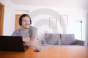 Young man wearing headphones watching series, videos, online classes on a laptop with the fan on