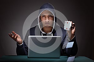 Young man wearing a hoodie sitting in front of a laptop computer