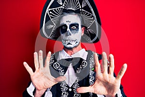 Young man wearing mexican day of the dead costume over red afraid and terrified with fear expression stop gesture with hands,