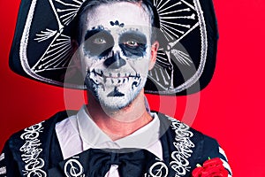 Young man wearing mexican day of the dead costume over red background looking positive and happy standing and smiling with a