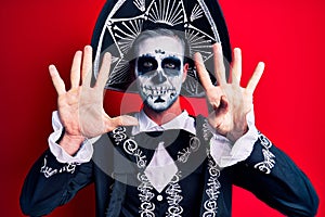 Young man wearing mexican day of the dead costume over red showing and pointing up with fingers number nine while smiling