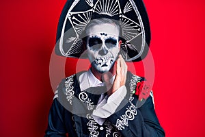 Young man wearing mexican day of the dead costume over red touching mouth with hand with painful expression because of toothache