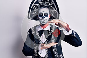 Young man wearing mexican day of the dead costume over white gesturing with hands showing big and large size sign, measure symbol