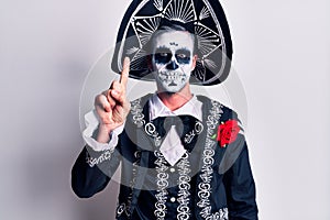 Young man wearing mexican day of the dead costume over white showing and pointing up with finger number one while smiling