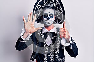 Young man wearing mexican day of the dead costume over white showing and pointing up with fingers number six while smiling